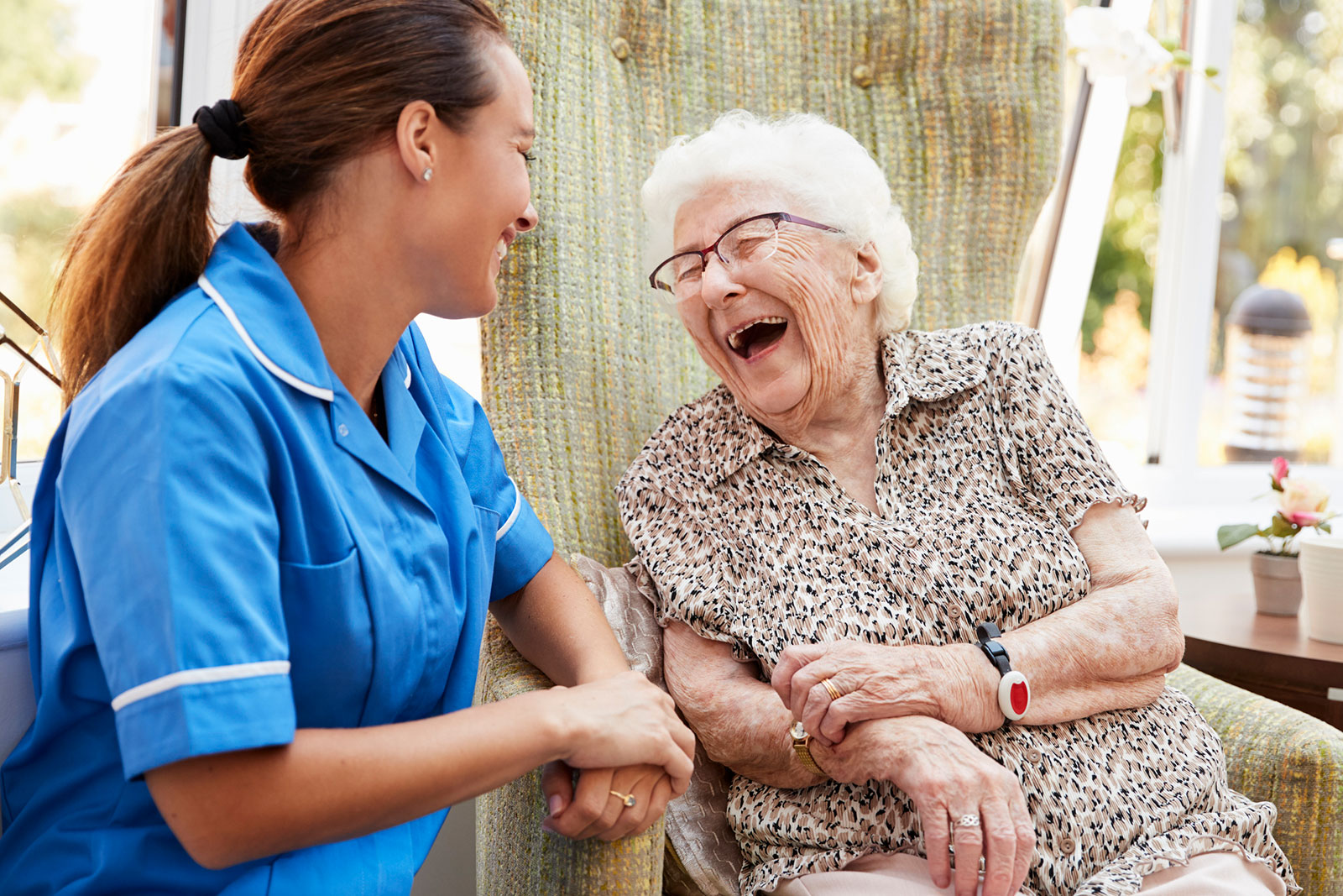 smiling caregiver and elderly woman talking